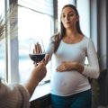 Pregnant woman declining glass of red wine. Adobe